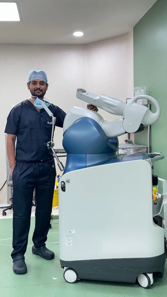 Dr. Arun Dev beside the robotic arm at Renova Hospital